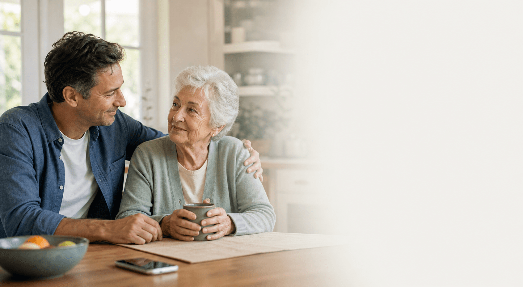 Adult son sitting with his elderly mother in a warm home setting
